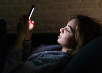 jovem com celular à noite