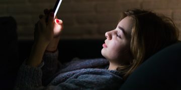 jovem com celular à noite
