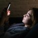 jovem com celular à noite